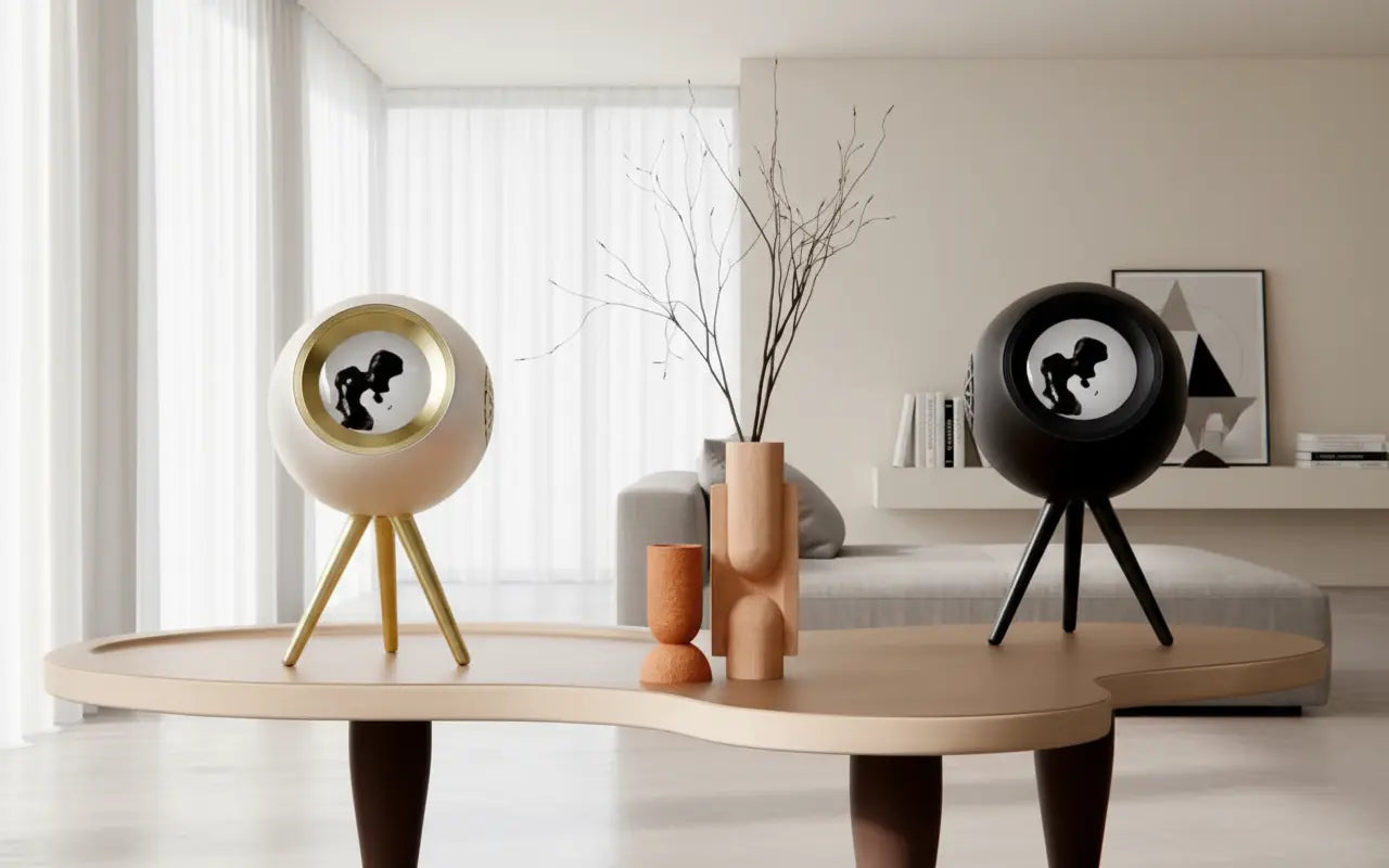 White and black Glowbe ferrofluid speakers displayed in a modern living room with real magnetic fluid visualization